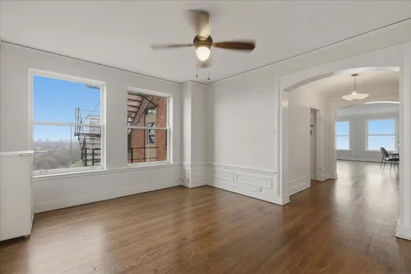 a view of an empty room with a window and wooden floor