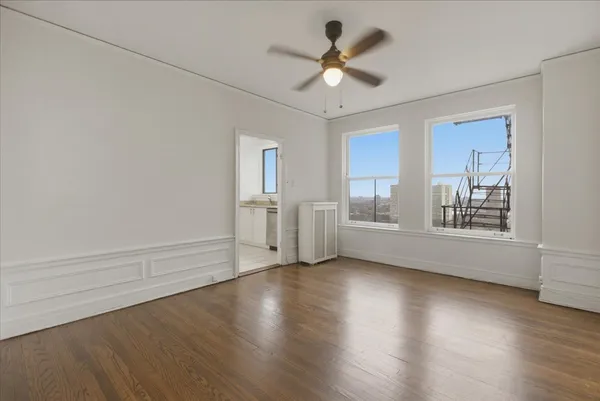a view of an empty room with a window and wooden floor