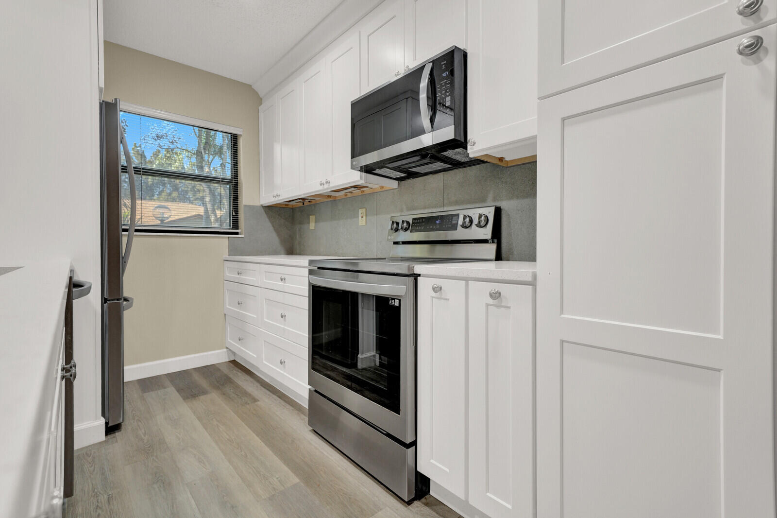 5270 Nesting Way, Unit C Delray Beach, FL 33484 - Photo 11 of 38 a kitchen with stainless steel appliances a stove microwave and refrigerator