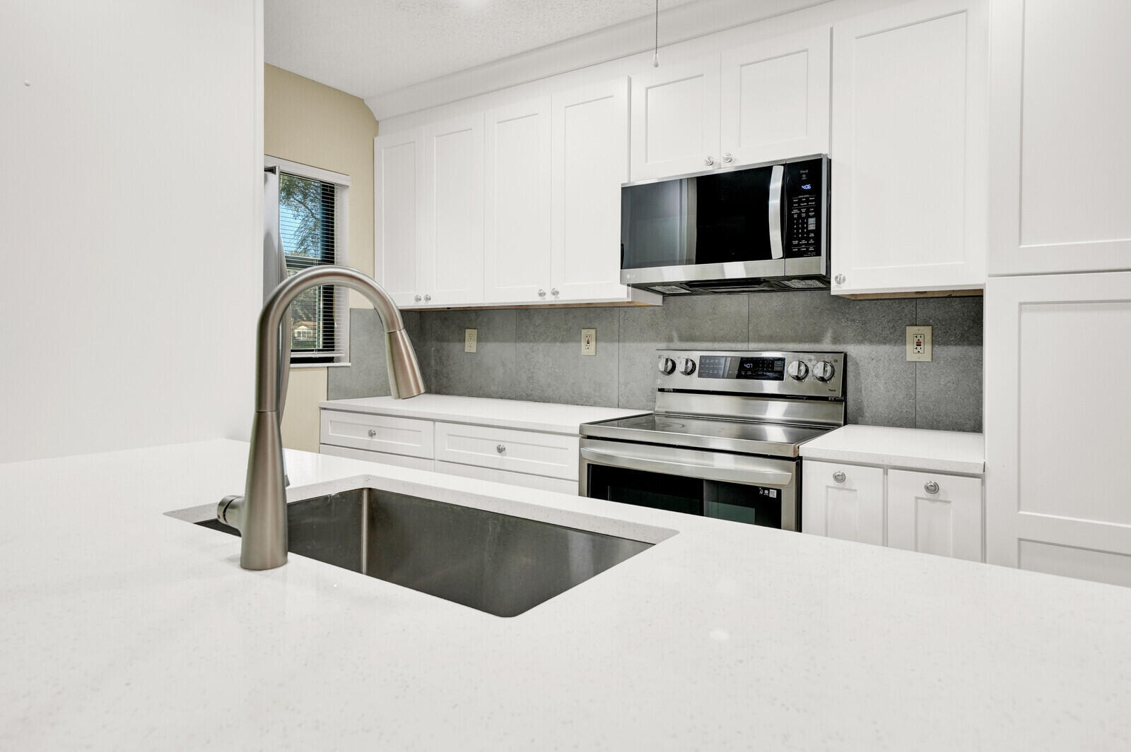 5270 Nesting Way, Unit C Delray Beach, FL 33484 - Photo 13 of 38 a kitchen with stainless steel appliances a stove microwave and sink