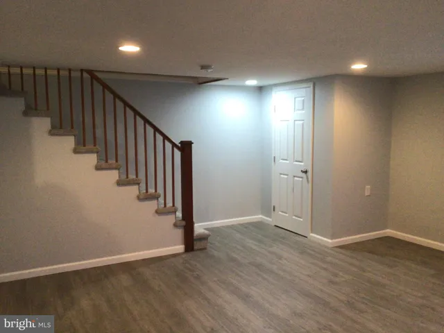 an empty room with wooden floor and staircase