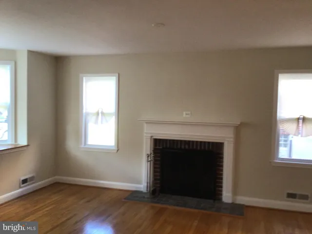 an empty room with windows and fireplace