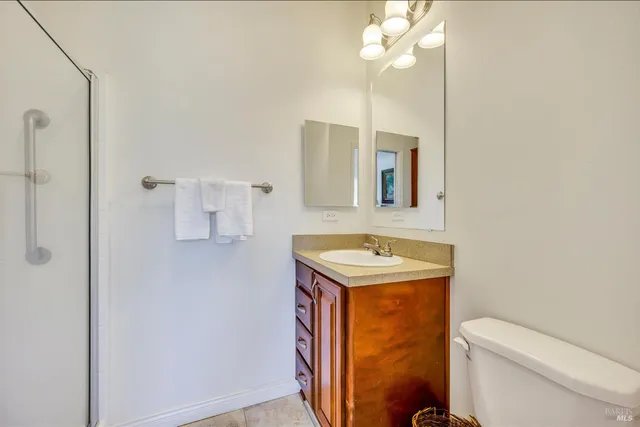 a bathroom with a granite countertop sink a toilet and mirror