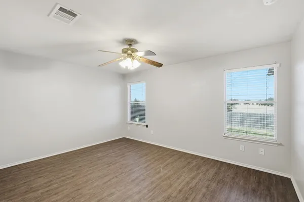 an empty room with wooden floor and windows