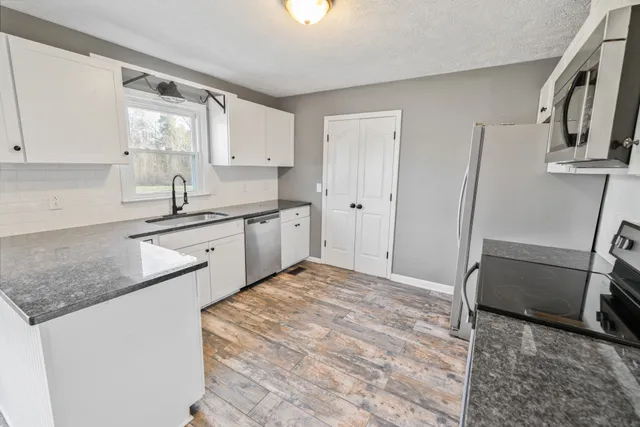 a kitchen with white cabinets and sink