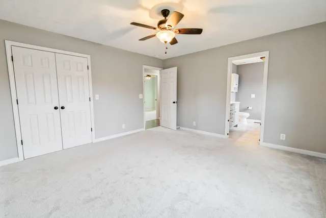 an empty room with a chandelier fan and windows