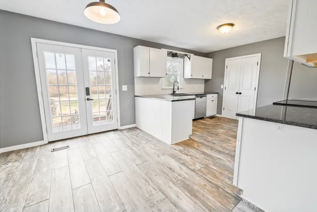 a large white kitchen with a refrigerator a stove a microwave and a dining table with wooden floor