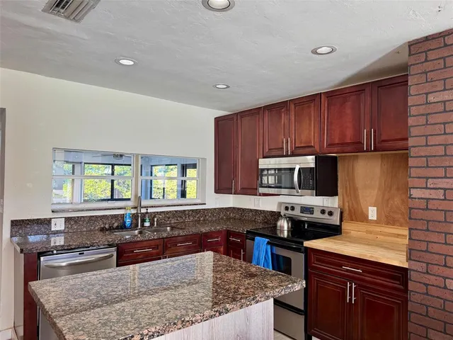 a kitchen with granite countertop wooden cabinets and a stainless steel appliances