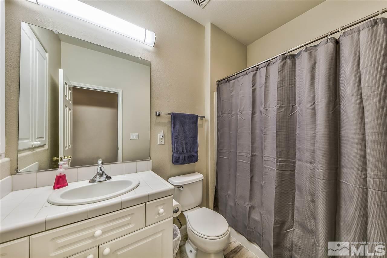 10680 Arbor Way Reno, NV 89521 - Photo 12 of 16 a bathroom with a sink a toilet a mirror and shower curtain