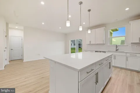 a kitchen with stainless steel appliances kitchen island granite countertop a stove top oven a sink a dining table and chairs with wooden floor