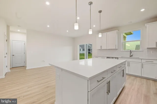 a kitchen with stainless steel appliances kitchen island granite countertop a stove top oven a sink a dining table and chairs with wooden floor