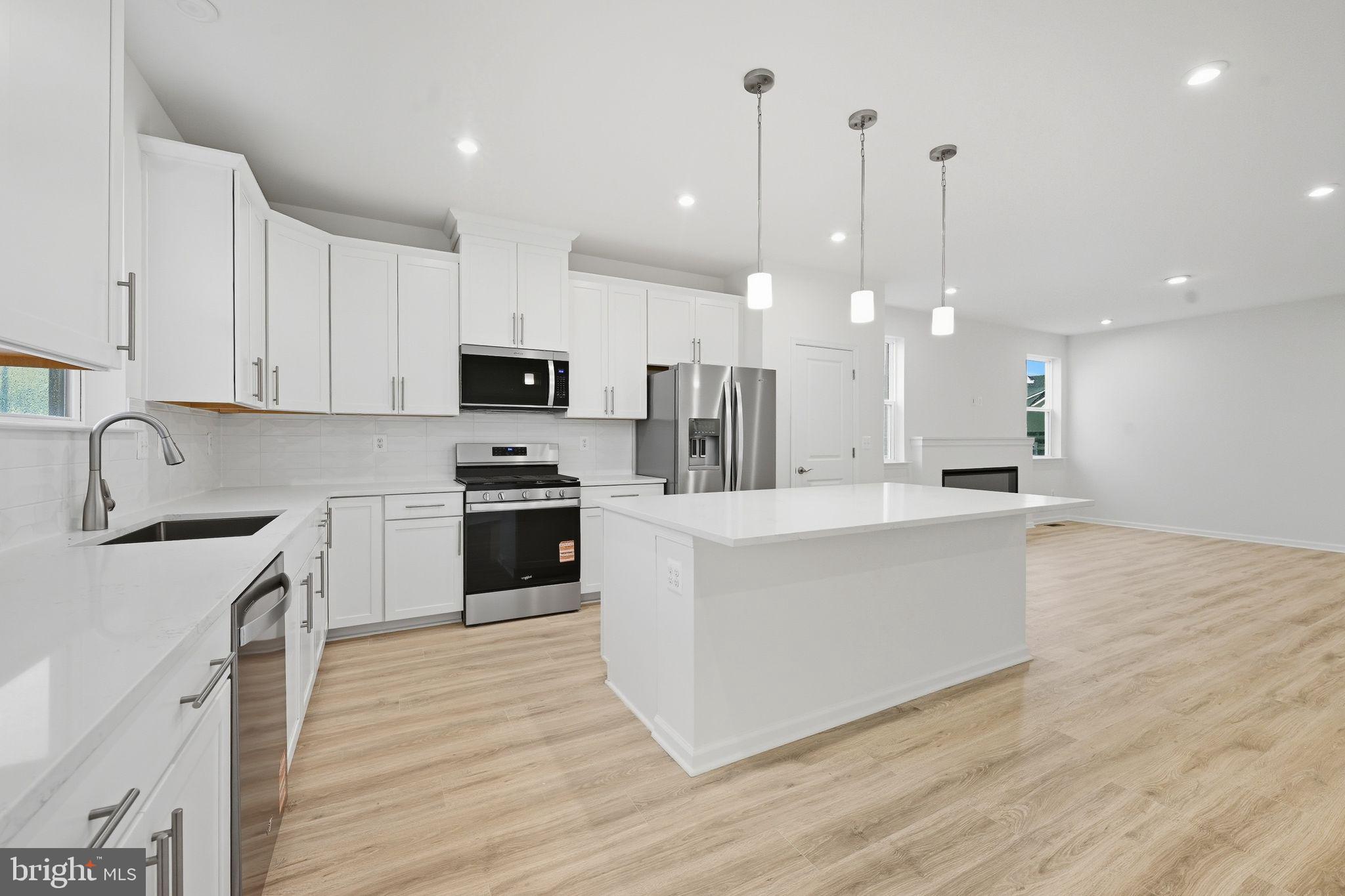 25013 Cypress Court Lewes, DE 19958 - Photo 15 of 24 a large kitchen with granite countertop a stove top oven a sink a counter space and cabinets