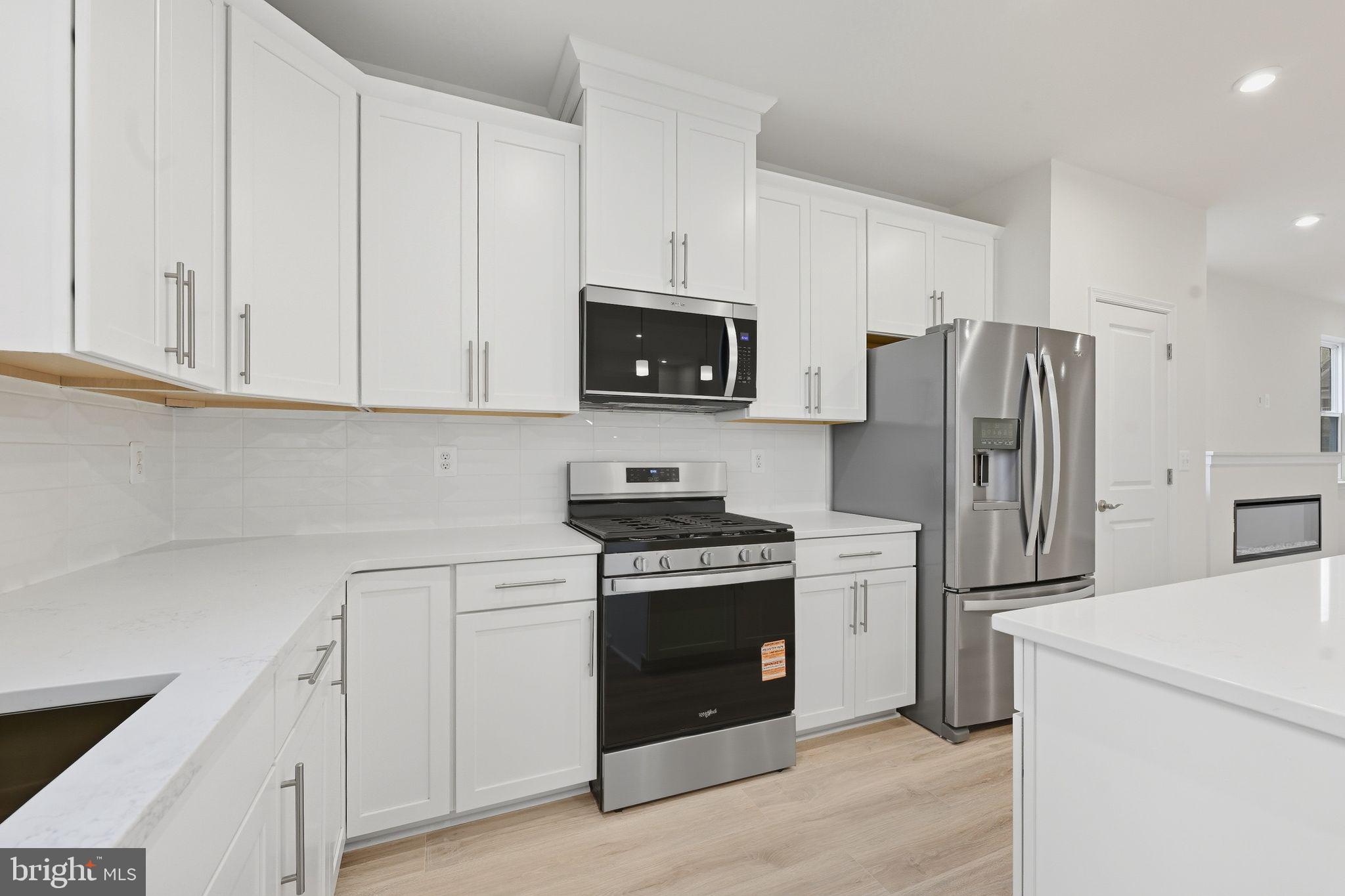 25013 Cypress Court Lewes, DE 19958 - Photo 17 of 24 a kitchen with stainless steel appliances granite countertop a stove a refrigerator and a microwave
