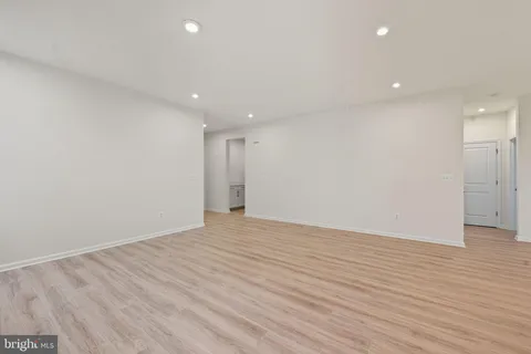 a kitchen with stainless steel appliances kitchen island granite countertop a refrigerator a stove a sink a dining table and chairs with wooden floor