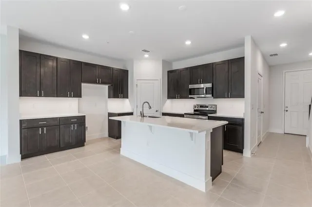 a kitchen with stainless steel appliances a stove top oven a sink a refrigerator and cabinets