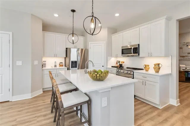 a kitchen with kitchen island a dining table chairs a sink and cabinets
