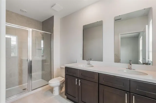 a bathroom with a double vanity sink toilet and shower