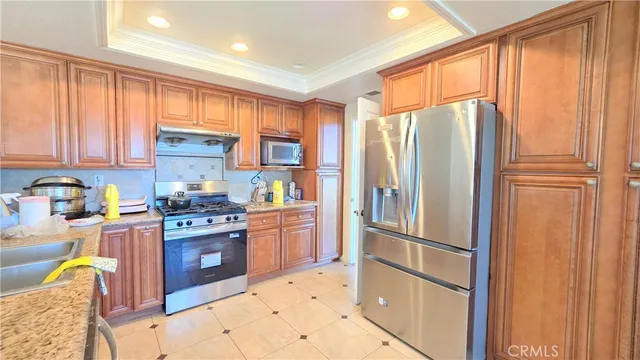 a kitchen with granite countertop stainless steel appliances a refrigerator stove top oven and sink