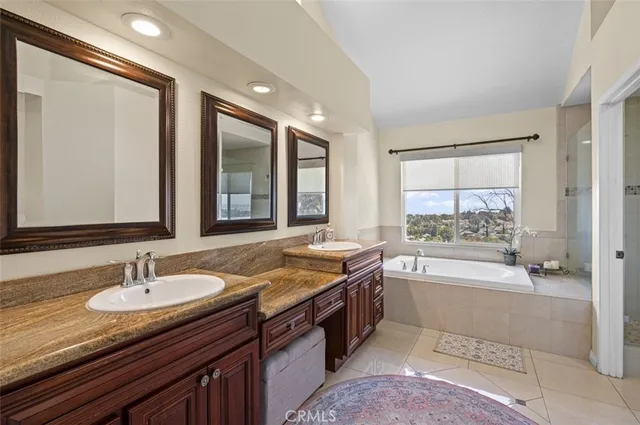 a bathroom with a granite countertop sink a mirror a bathtub and next to a window