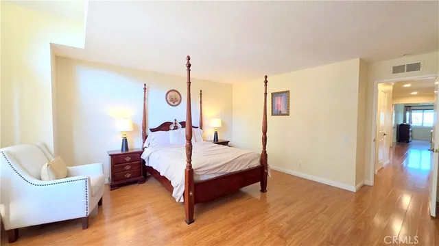 a bedroom with a bed a couch and wooden floor