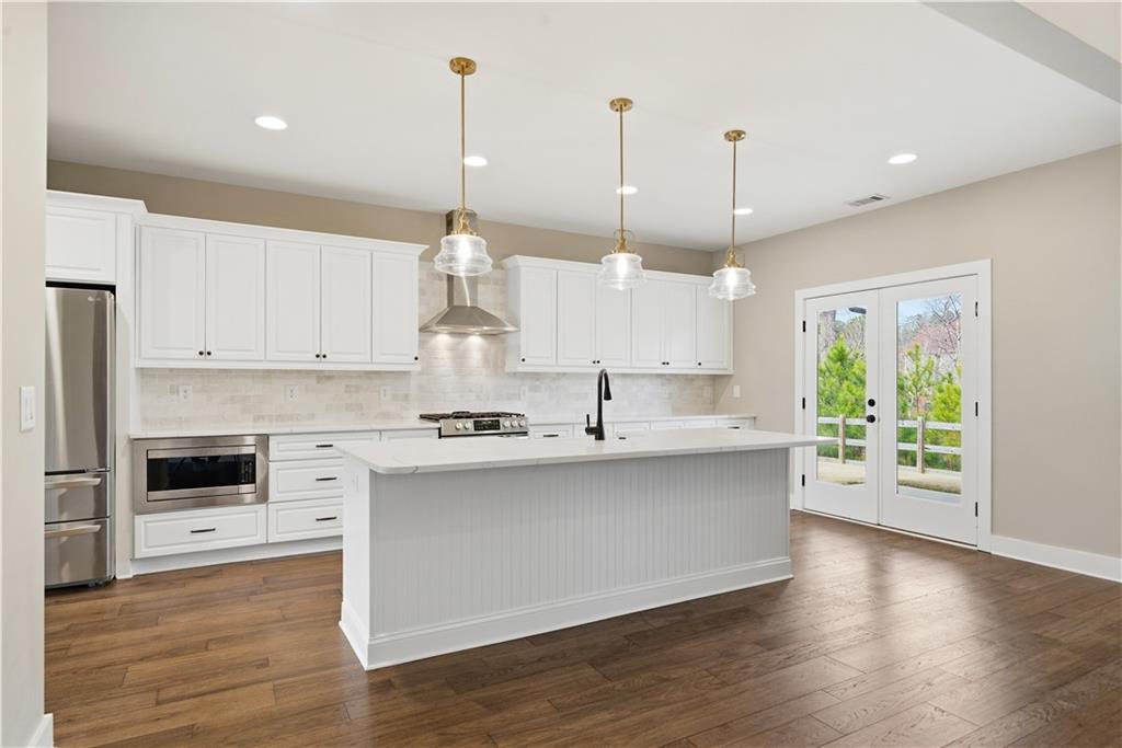 12 Bridgestone Way Cartersville, GA 30120 - Photo 19 of 46 a large kitchen with stainless steel appliances a large counter top a stove a chimney a sink and a wooden floors