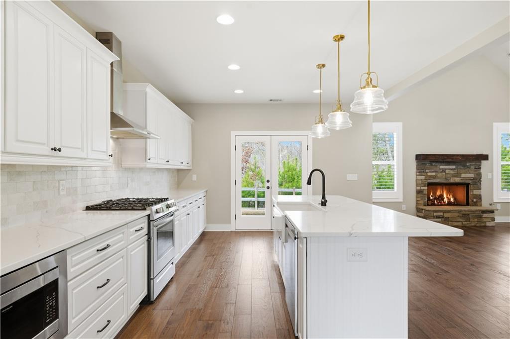 12 Bridgestone Way Cartersville, GA 30120 - Photo 4 of 46 a large kitchen with stainless steel appliances granite countertop a stove a sink a chimney wooden floor and cabinets