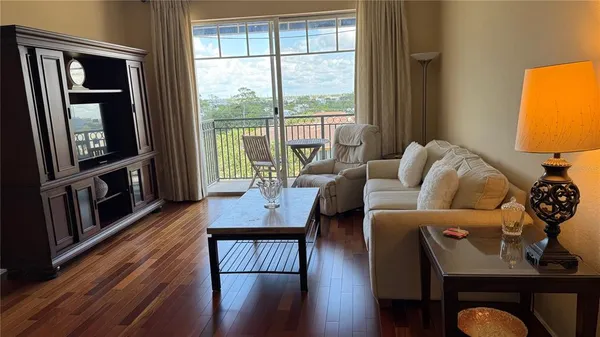 a living room with furniture a large window and wooden floor