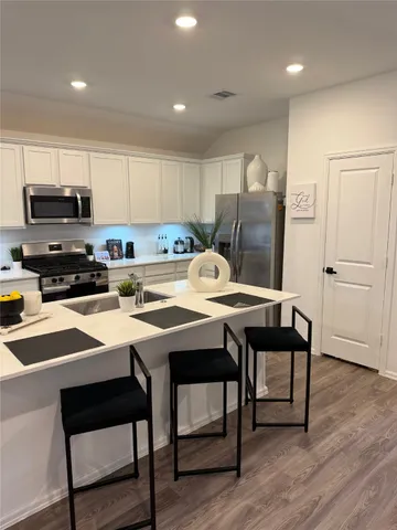 a kitchen with stainless steel appliances a table chairs refrigerator and microwave
