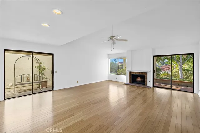 a view of an empty room with wooden floor fireplace and a window