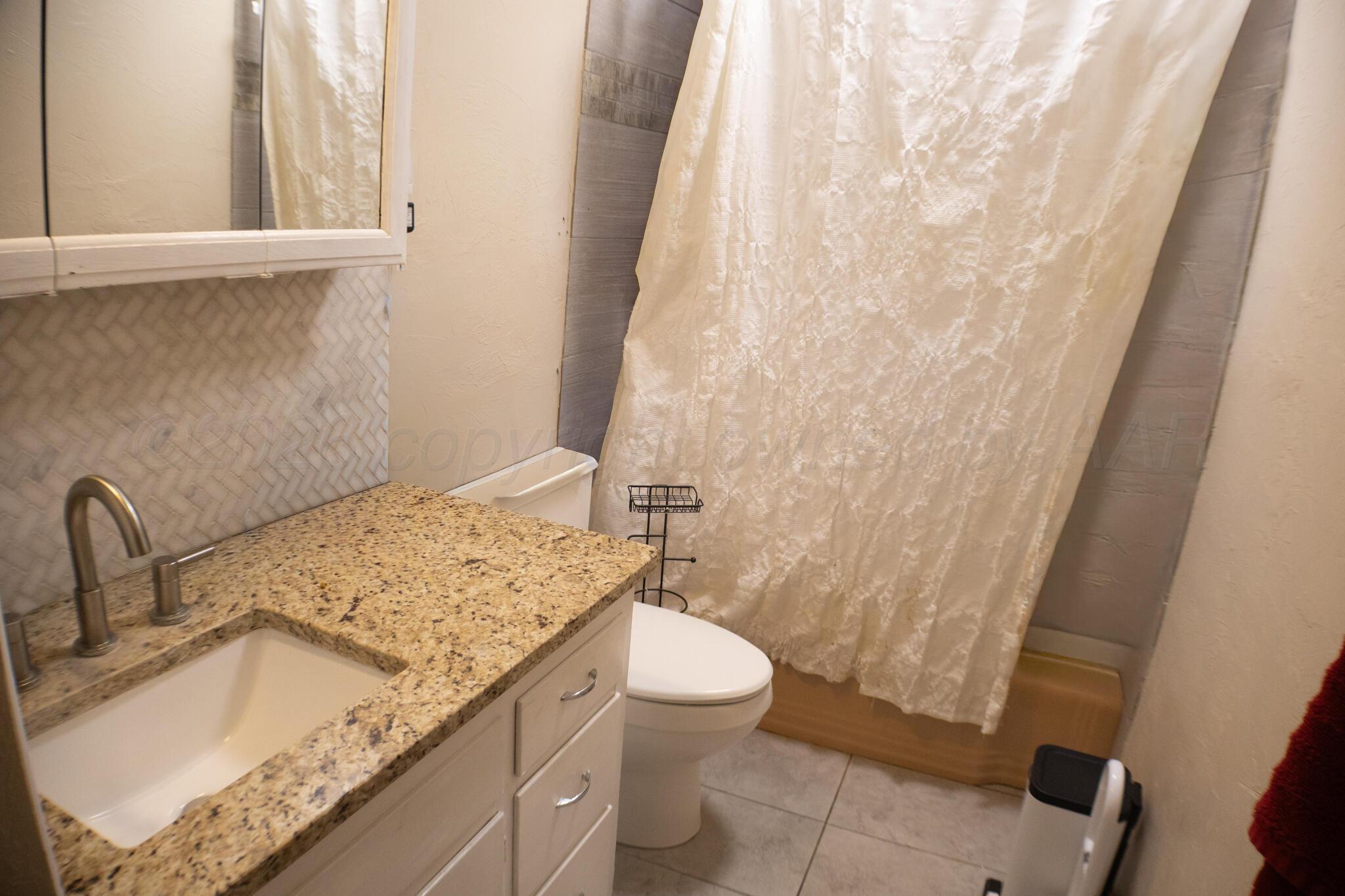 4711 South Rusk Street Amarillo, TX 79110 - Photo 13 of 24 a bathroom with a granite countertop sink toilet and a mirror
