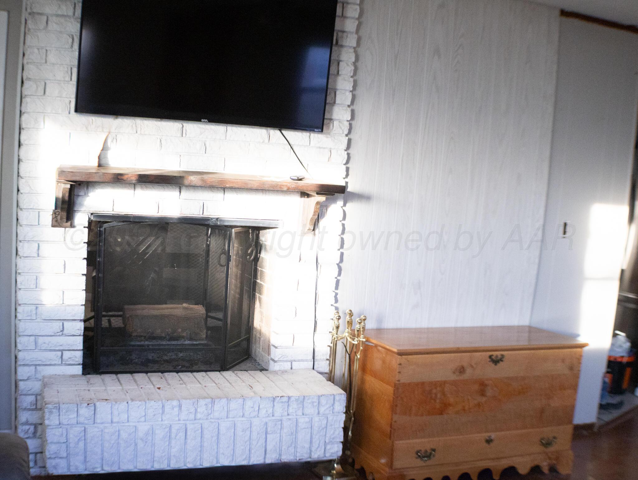 4711 South Rusk Street Amarillo, TX 79110 - Photo 6 of 24 a living room with a fireplace furniture and a flat screen tv