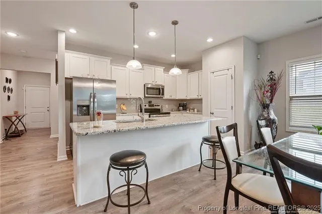 a kitchen with stainless steel appliances granite countertop a table chairs stove microwave and cabinets