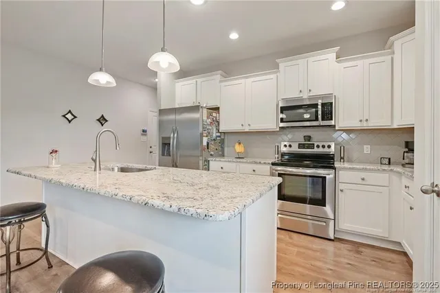 a kitchen with kitchen island granite countertop a sink a counter space appliances and cabinets
