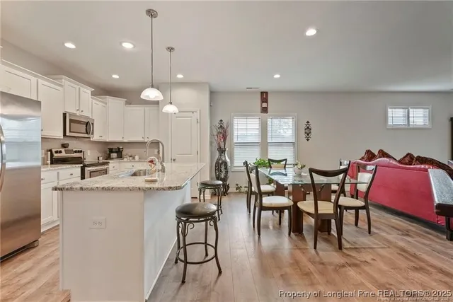 a kitchen with stainless steel appliances kitchen island granite countertop a dining table chairs and sink