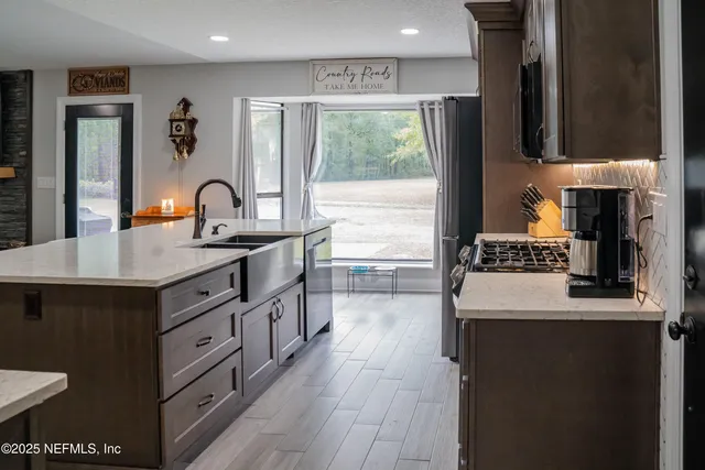 a kitchen with stainless steel appliances granite countertop a table chairs and a refrigerator
