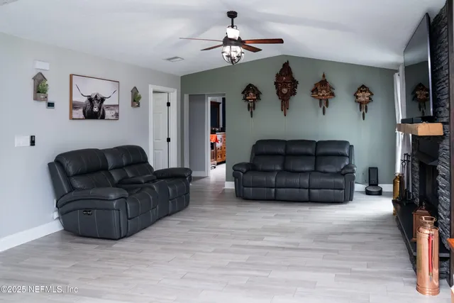 a view of an empty room with wooden floor and a fireplace
