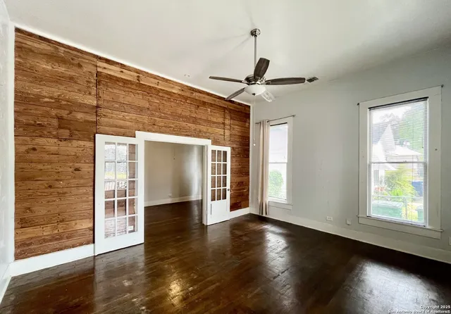 a view of an empty room with wooden floor and a window