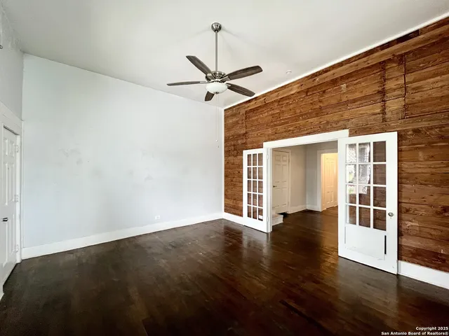 an empty room with wooden floor ceiling fan and windows
