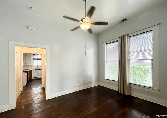 a view of empty room with wooden floor and fan