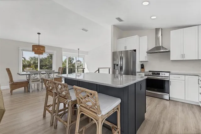 a kitchen with stainless steel appliances a dining table chairs and wooden floor