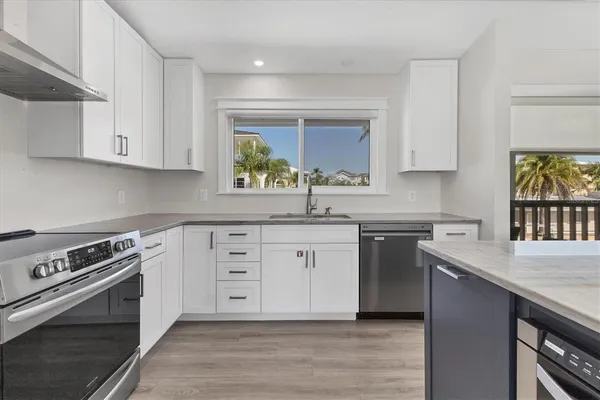 a kitchen with stainless steel appliances white cabinets a stove a sink and a window