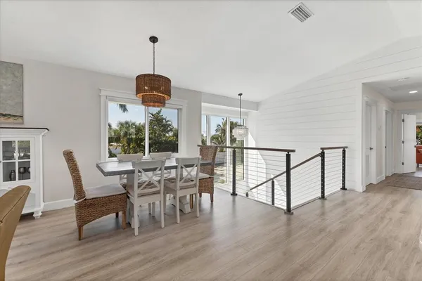 a dining room with wooden floor a chandelier a glass table and chairs