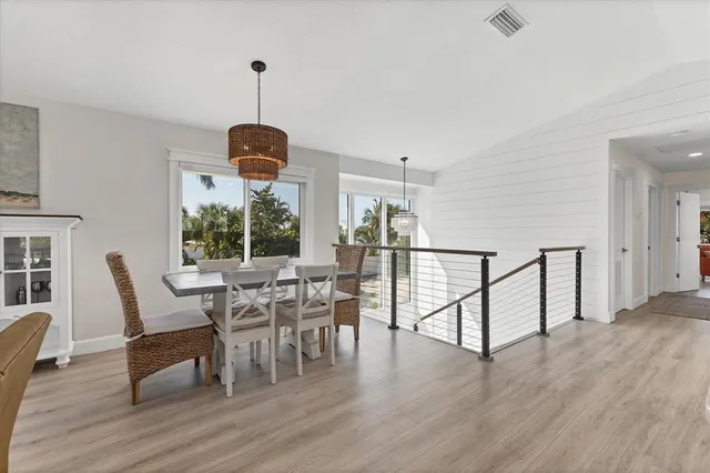 a dining room with wooden floor a chandelier a glass table and chairs