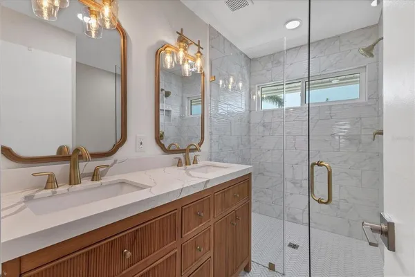 a bathroom with a double vanity sink mirror and shower