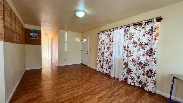 a view of an empty room with wooden floor and a shower curtain