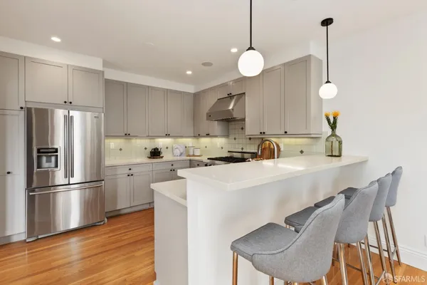 a kitchen with stainless steel appliances a stove a sink a refrigerator a center island and cabinets