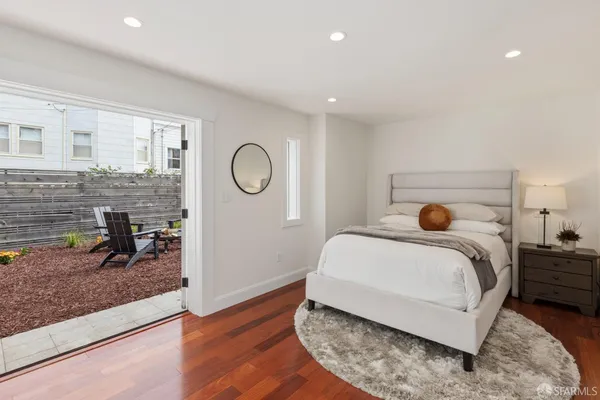 a bedroom with a bed and a dresser with wooden floor