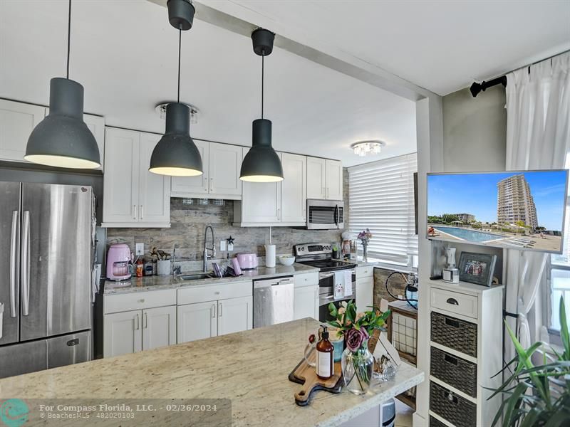 a kitchen with stainless steel appliances a stove a sink dishwasher a refrigerator and cabinets