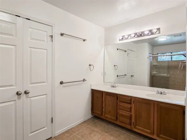 a spacious bathroom with a double vanity sink a large mirror and shower