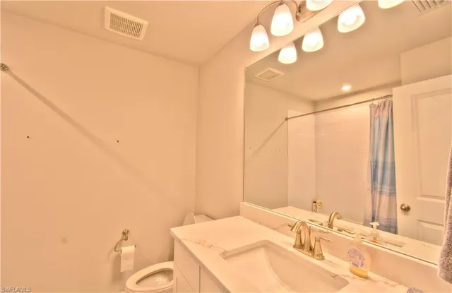 a bathroom with a granite countertop sink mirror and a toilet